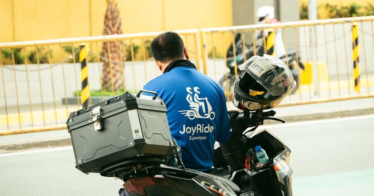 Motosikletinin yanında evrak inceleyen kurye